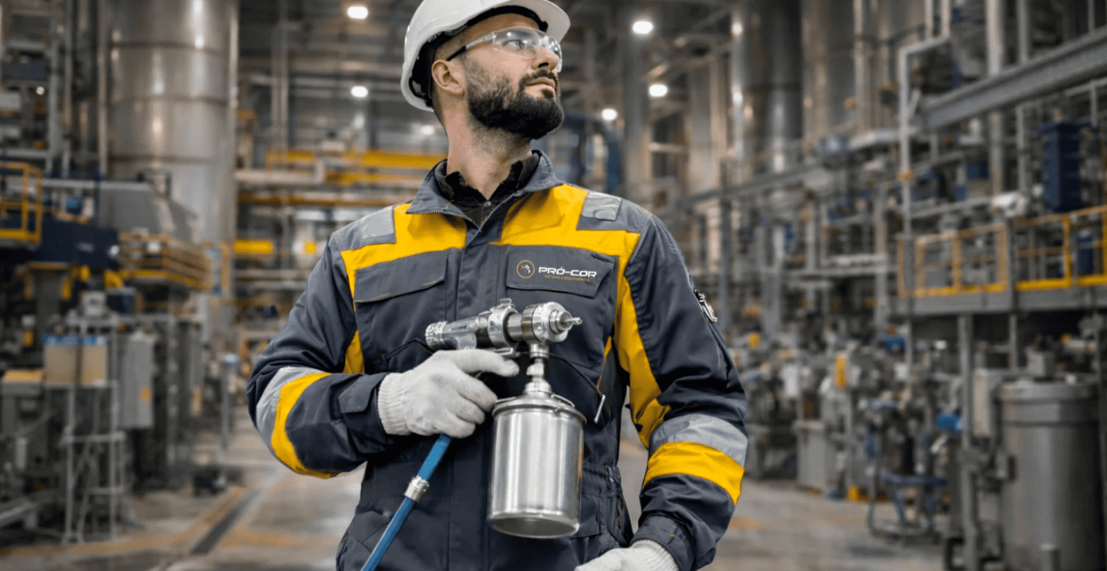 Profissional Pró Cor com equipamento de pintura em planta industrial